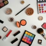 A vibrant collection of makeup and beauty products arranged in a flat lay on a white background.