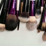 A collection of makeup brushes with soft bristles arranged on a white background in a flat lay style.